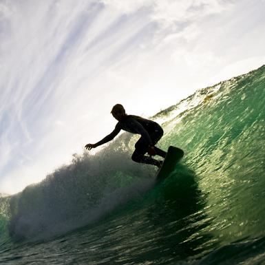 Ocean and cloudy sky with silhouette of surfer