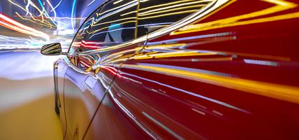 Red electric powered car drives on city highway while night