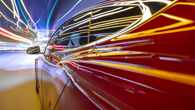 Red electric powered car drives on city highway while night