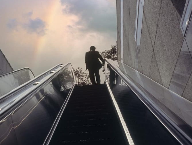 man walking up escalator