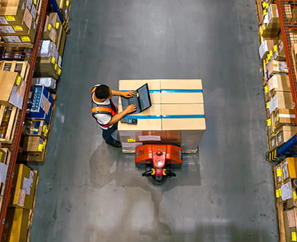 overhead view of a man working on laptop in warehouse
