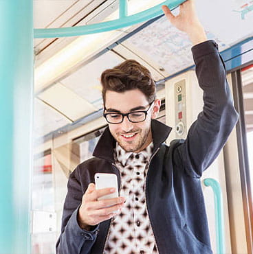 Man standing in public transport looking at phone