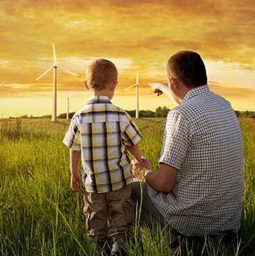 father shows son some wind turbines in a field