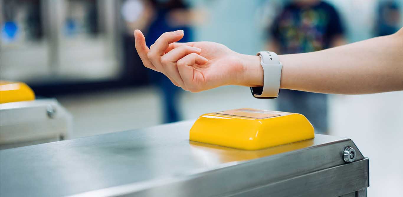 woman checking in at subway station using contactless payment for subway ticket via smartwatch