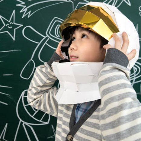 Wearing a helmet of astronauts little boy standing in front of the blackboard
