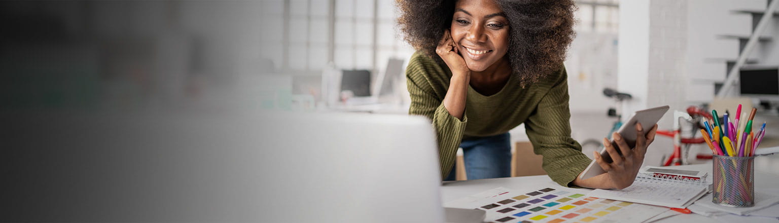 black lady with curly hairs looking at laptop and smiling