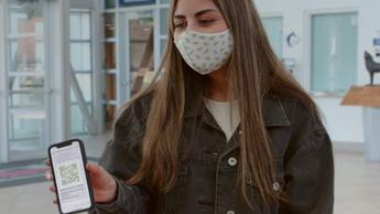 College student with mask showing phone app