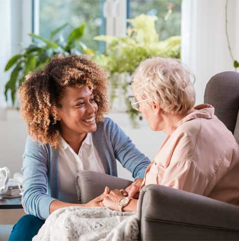 woman talking to older woman sitting in chair