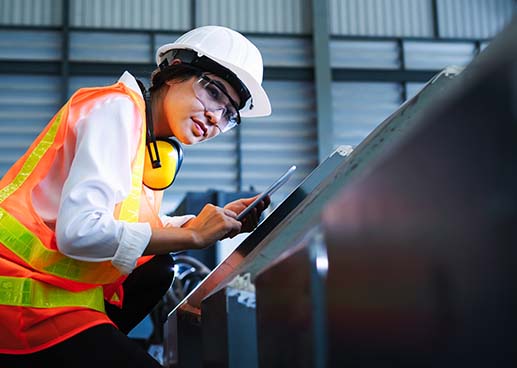 woman in hard hat sanding something metallic