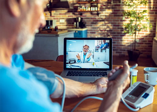 Person taking blood pressure while on a video call with a doctor