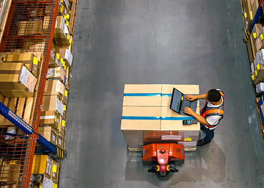 overview of man working at laptop in warehouse