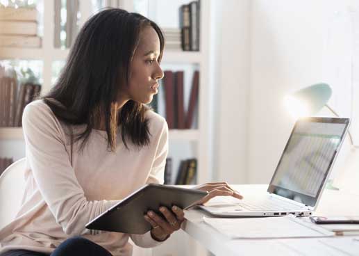 woman working at computer while holding tablet