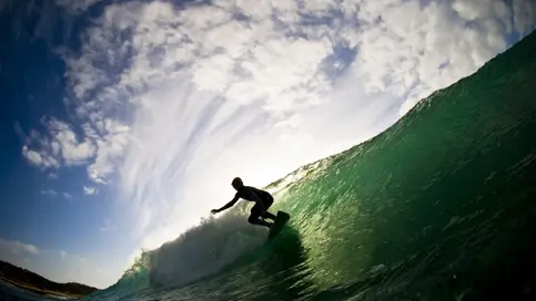 Ocean and cloudy sky with silhouette of surfer