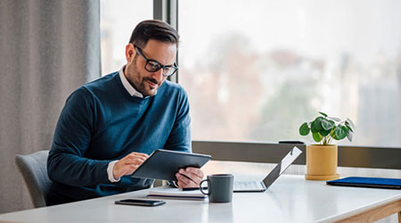 man looking at tablet in front of window