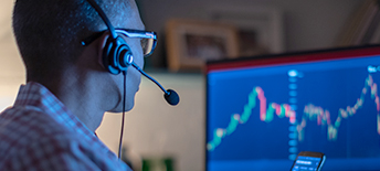 man wearing headset looking at graph on screen