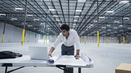  Indian architect using laptop in empty warehouse