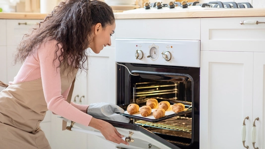 woman taking food out of an oven