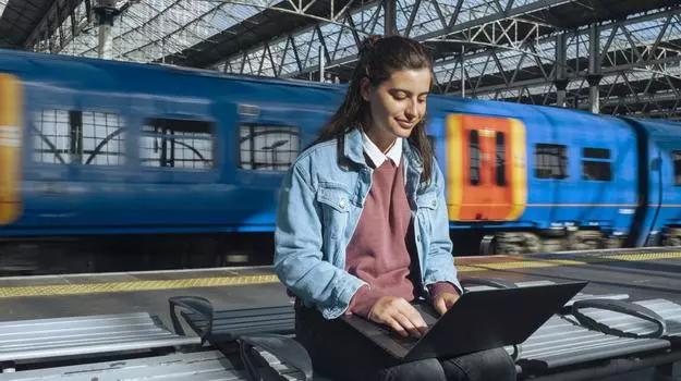 woman sitting on laptop in front of train