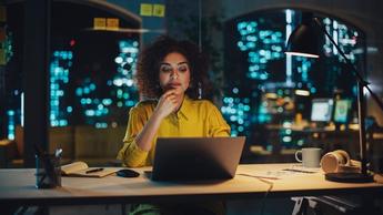 Woman working on laptop with desk lamp