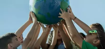group of children holding up a globe