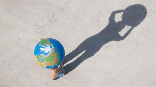 boy holding a globe with his shadow on the ground