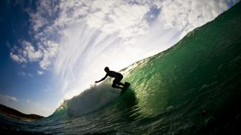 Ocean and cloudy sky with silhouette of surfer