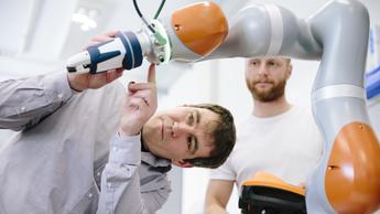 two engineers work at a robotic arm