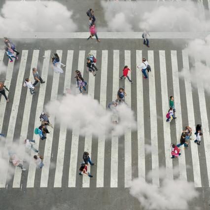 overhead shot of people walking on crosswalk on street with clouds above their heads