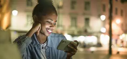 Portrait of happy young woman using smartphone in the city