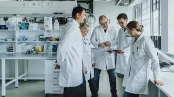 Team of scientist with digital tablet working together while standing at laboratory