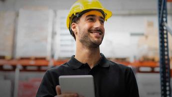 Man in hard hat happily working in warehouse