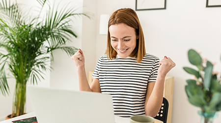 woman excitedly looking at laptop screen