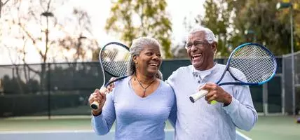 A senior black couple leaving the tennis court after their workout.