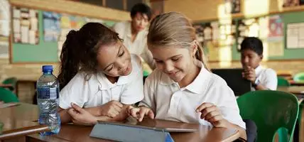 Schoolgirls looking at tablet together and smiling