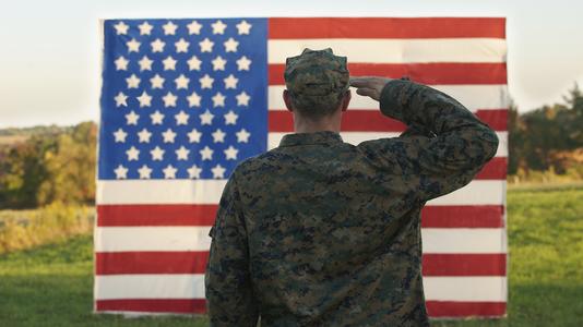 A soldier in the army salutes the USA flag