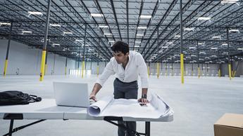  Indian architect using laptop in empty warehouse