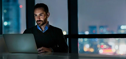 Man viewing laptop computer in office at night