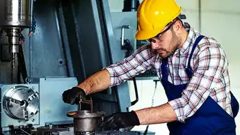 worker with safety helmet on his head, working with machines in workshop