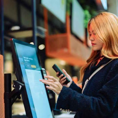 woman at touch screen with mobile