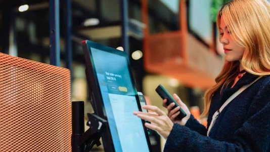 woman at touch screen with mobile