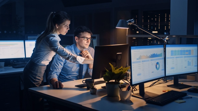 Businessman and businesswoman using a computer during a late night at work