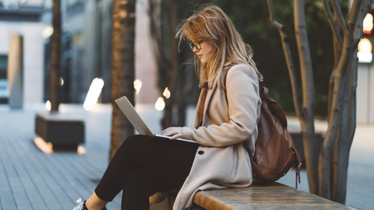 woman on laptop outside on bench