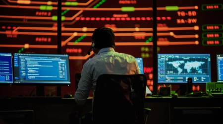 man wearing headset working in room of screens