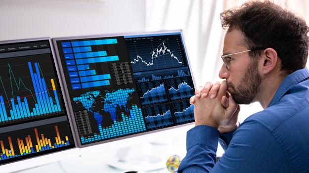 man looking pensively at a computer displaying graphs