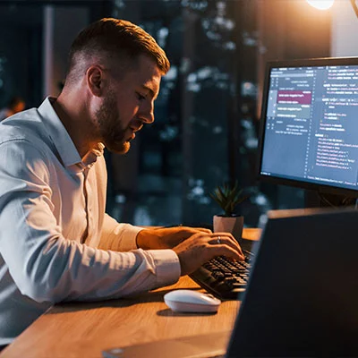 Young businessman in formal clothes is in office with multiple screens