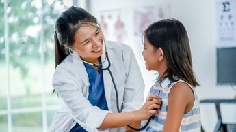 The girl is getting a checkup from the doctor and smiling