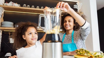 The girl is cooking with her mom.