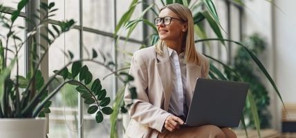 woman sitting among plants looking out window