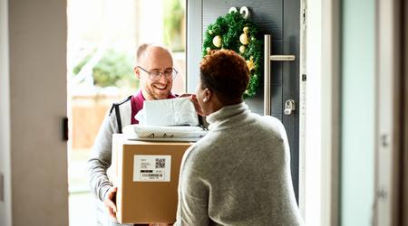 Woman checking delivery with cheerful courier at front door