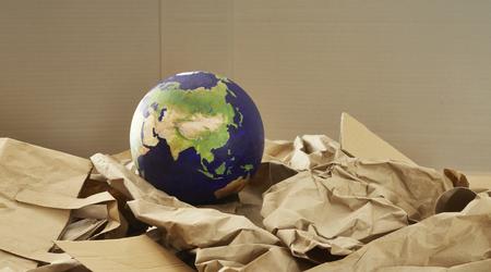 A world globe on a stack of paper recyclables